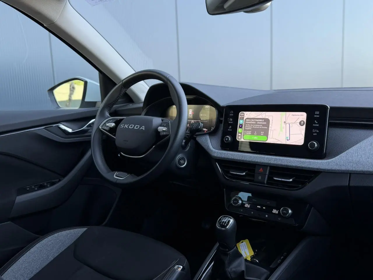 Vue intérieure côté conducteur du Skoda Scala TSI 116 blanc, avec volant cuir et écran tactile central allumé.