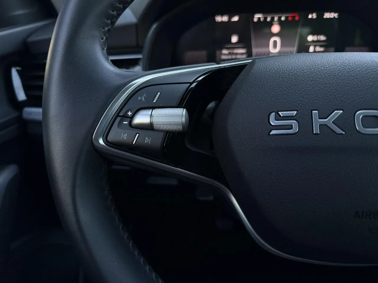 Gros plan sur le volant cuir noir de la Skoda Scala TSI 116, avec commandes multifonctions et tableau de bord digital flou.