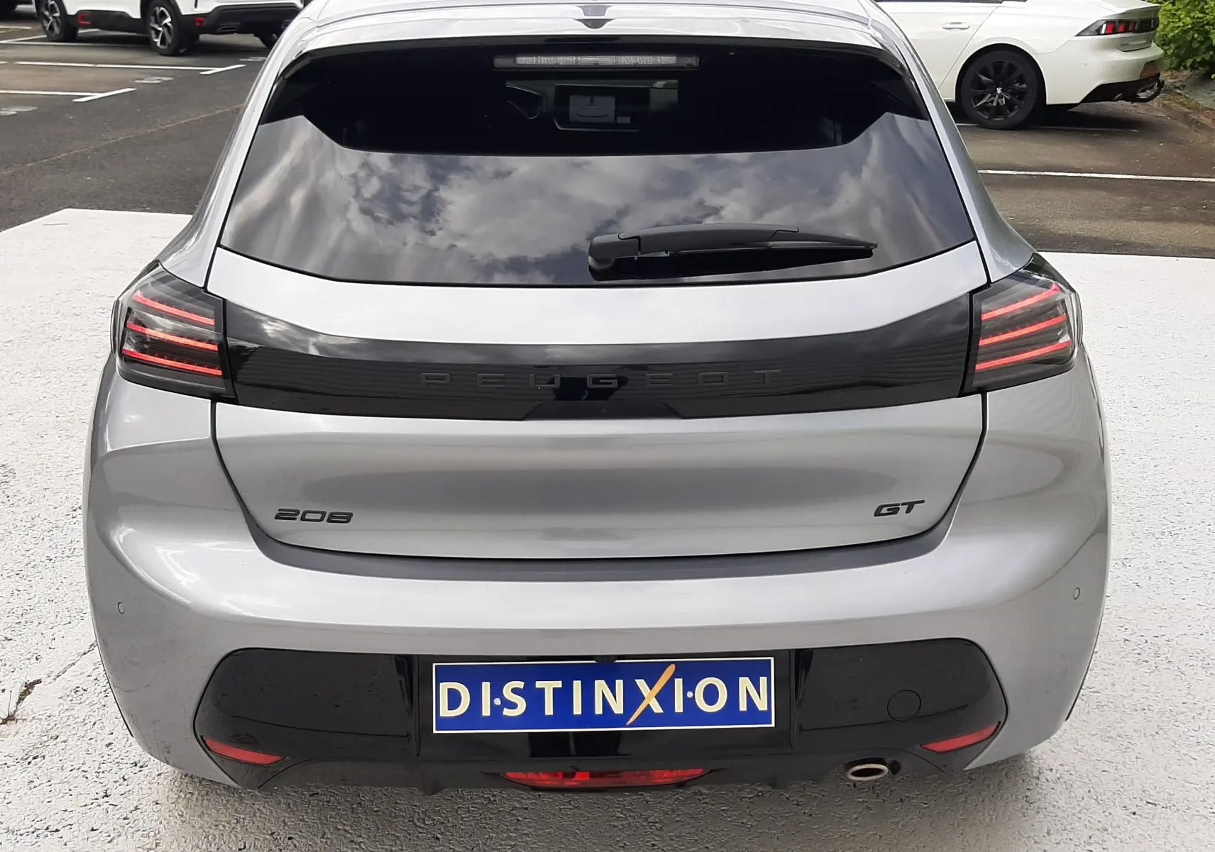 Vue arrière d'une Peugeot 208 GT gris Artense avec feux LED distinctifs et vitre arrière teintée.