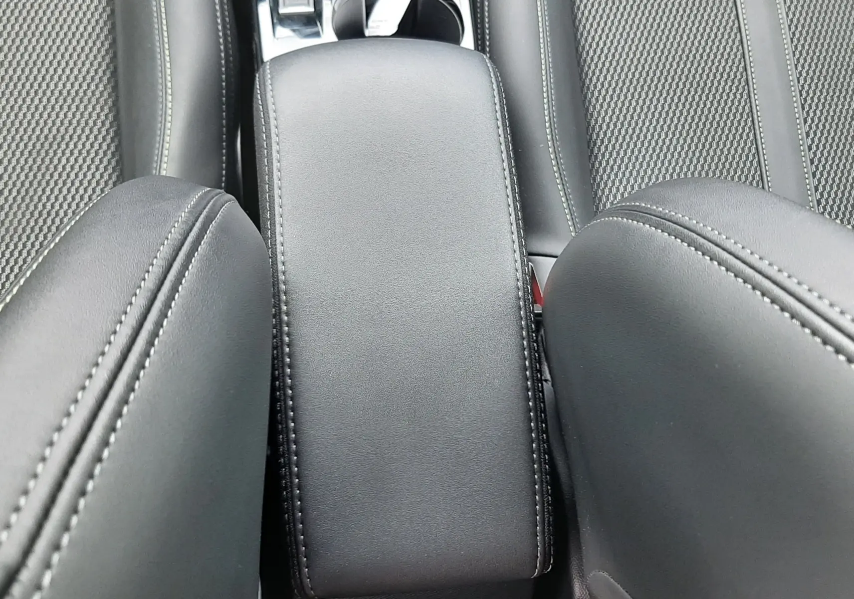 Vue plongeante sur l'accoudoir central et les sièges en cuir noir de la Peugeot 208 1.2 GT 2025.