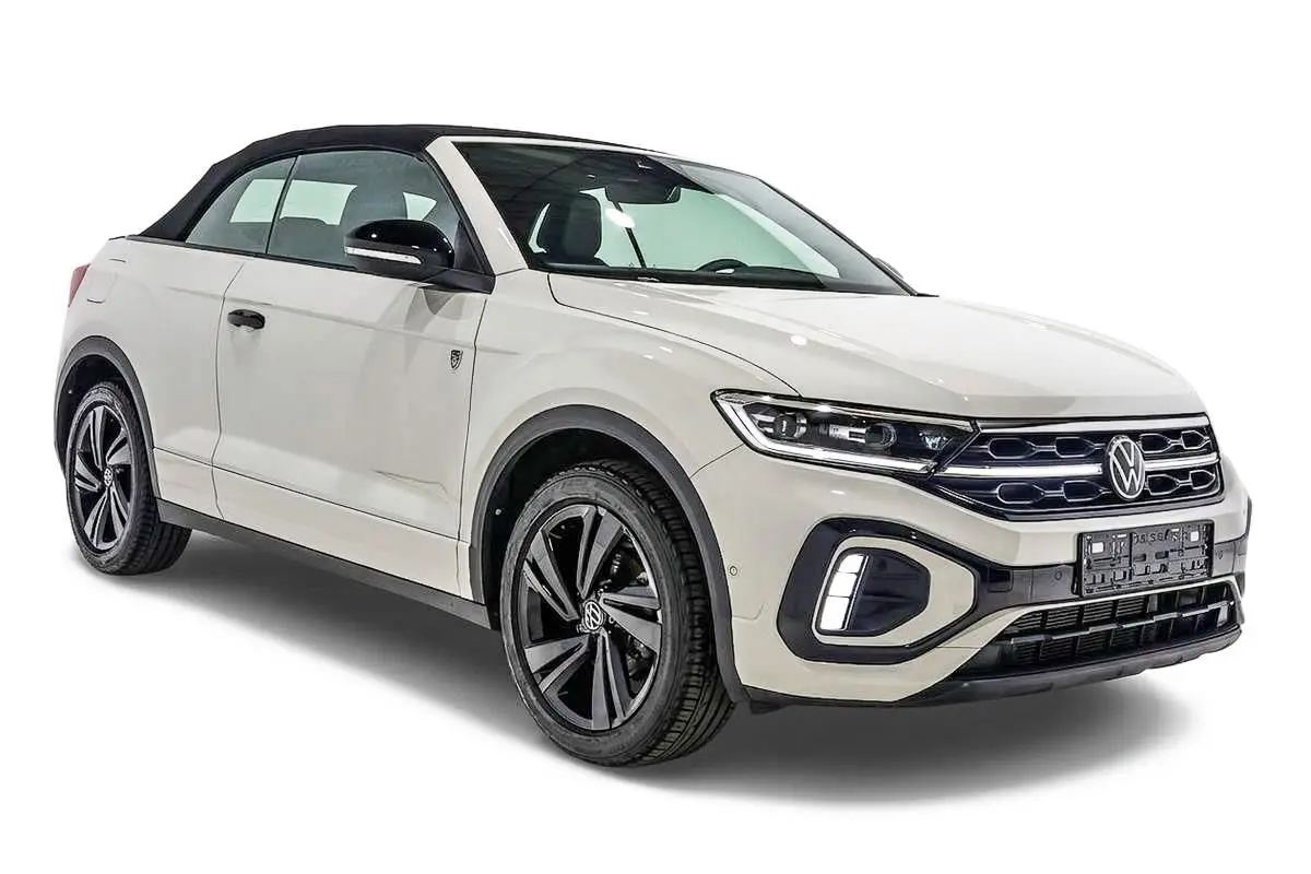 Vue 3/4 avant droite d’un Volkswagen T-Roc Cabriolet beige métallisé avec toit noir et jantes noires distinctives.