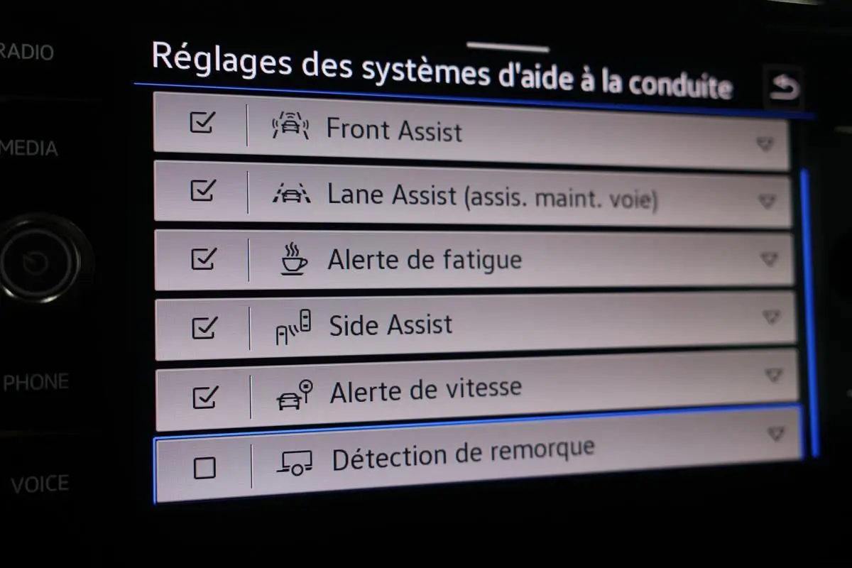 Vue intérieure de l’écran tactile du Volkswagen T-Roc Cabriolet beige, affichant les réglages des aides à la conduite.