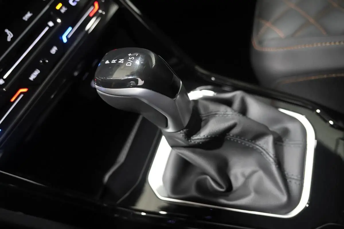 Le levier de vitesses automatique noir et argenté du Volkswagen T-Roc Cabriolet, avec coutures visibles sur le cuir environnant.