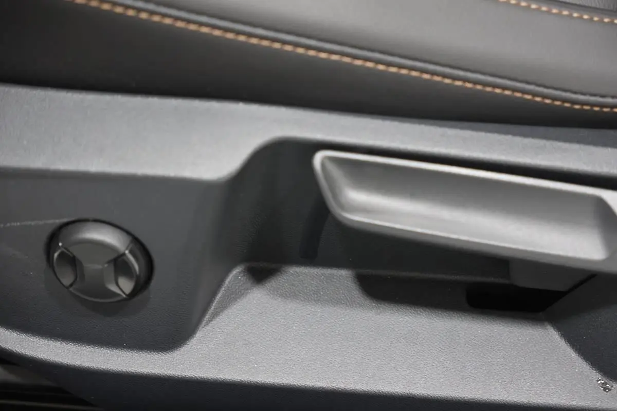 Détail de la commande de réglage manuel du siège côté gauche dans l’habitacle d’un Volkswagen T-Roc Cabriolet beige métallisé.