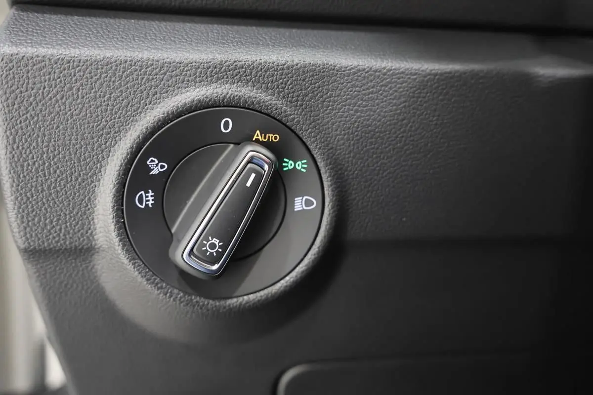 Gros plan sur le bouton de commande des phares dans l’habitacle du Volkswagen T-Roc Cabriolet beige métallisé.