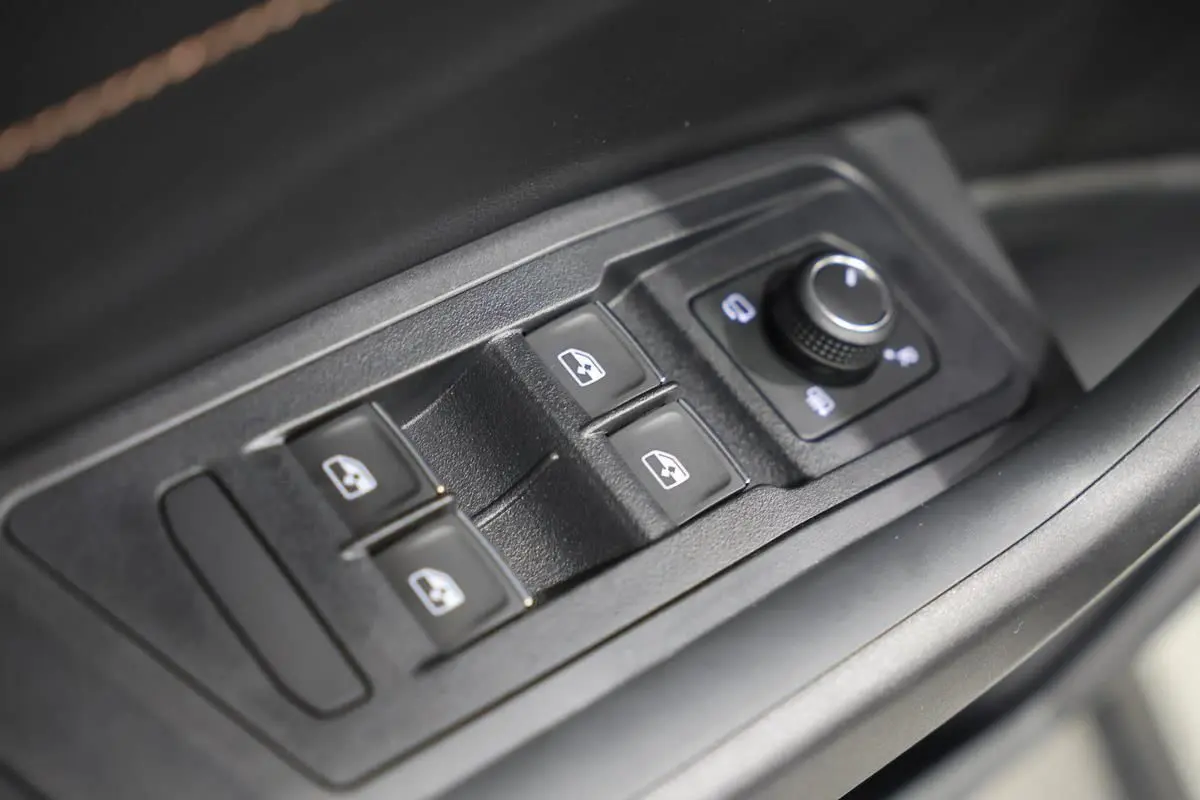 Gros plan sur les commandes de lève-vitres et réglage des rétroviseurs côté conducteur d’un Volkswagen T-Roc Cabriolet.