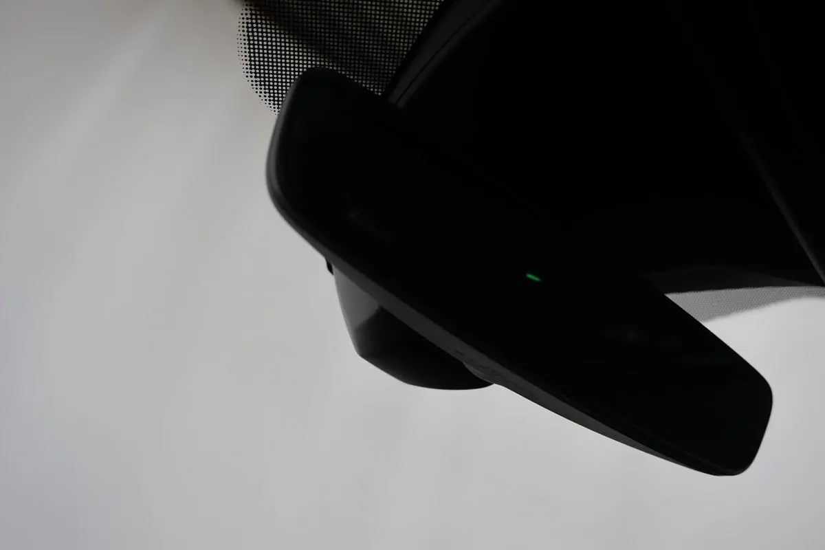 Rétroviseur intérieur noir avec témoin lumineux vert, vue rapprochée depuis l'habitacle du Volkswagen T-Roc Cabriolet beige.