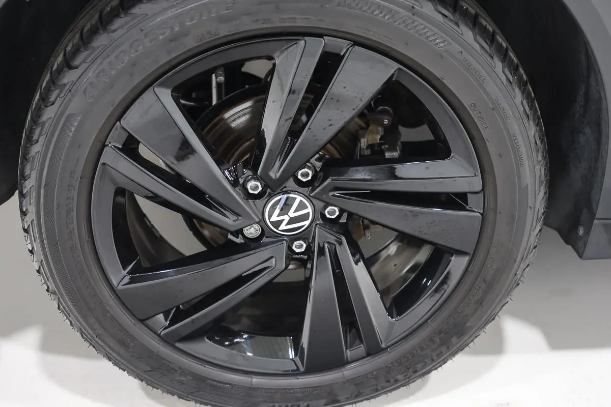 Gros plan sur la jante noire brillante avec logo Volkswagen, montée sur un pneu Bridgestone.