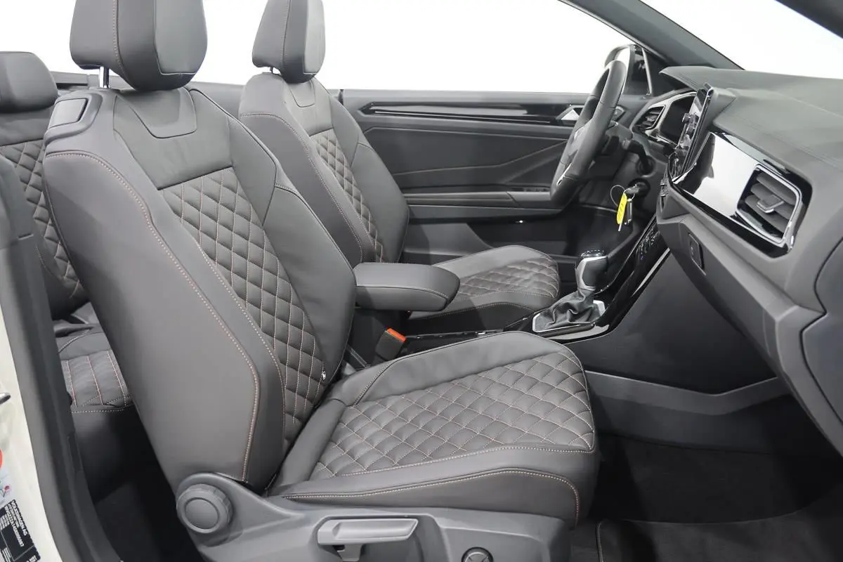 Vue intérieure côté droit du Volkswagen T-Roc Cabriolet 2025, sièges en cuir noir matelassé avec surpiqûres contrastées.