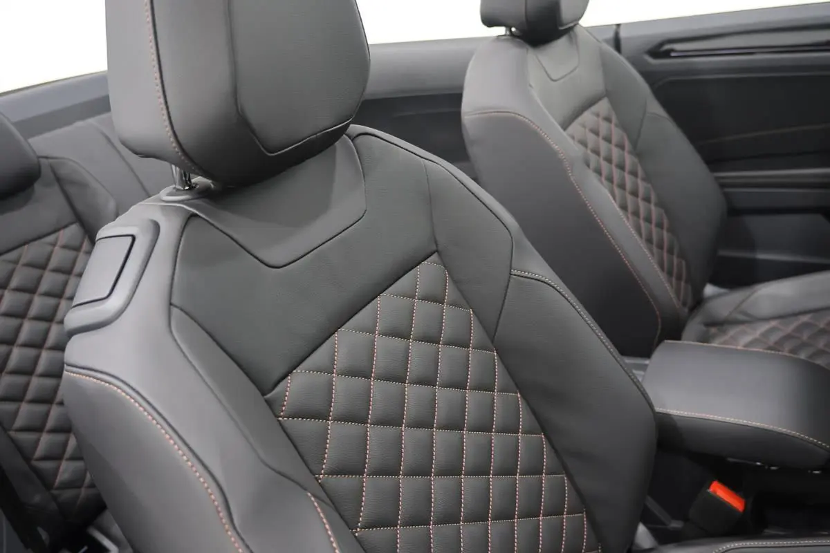 Gros plan sur les sièges avant en cuir noir avec surpiqûres marron, intérieur du Volkswagen T-Roc Cabriolet 2025.