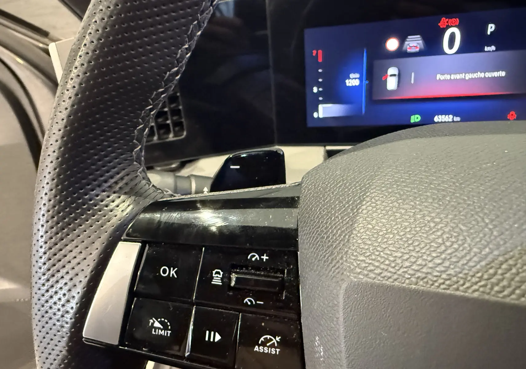 Gros plan sur les commandes à gauche du volant perforé de l'Opel Astra Sports Tourer 2024, avec affichage digital en arrière-plan.