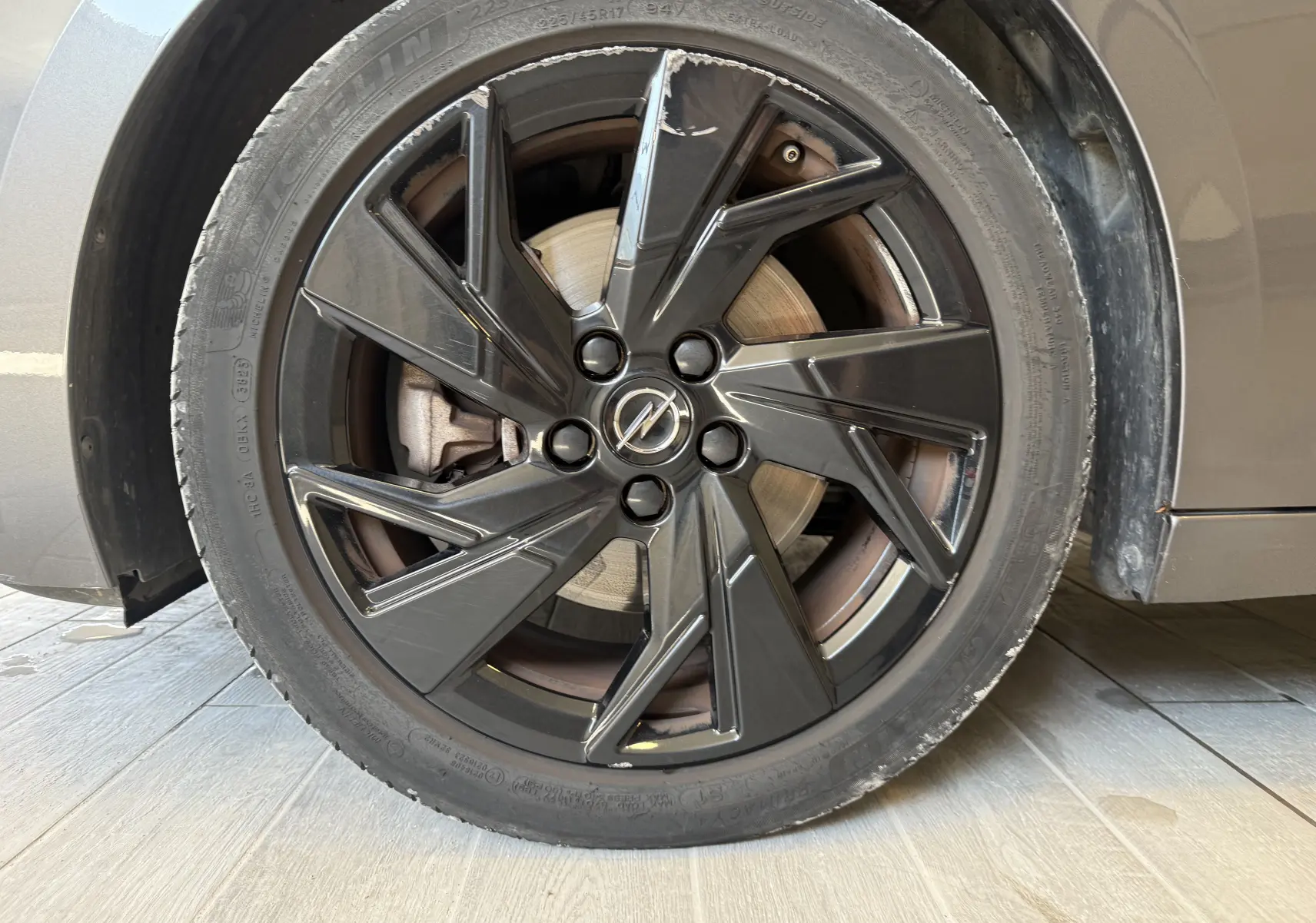 Gros plan sur la roue avant gauche de l’Opel Astra Sports Tourer gris, avec jante noire au design moderne et logo Opel central.