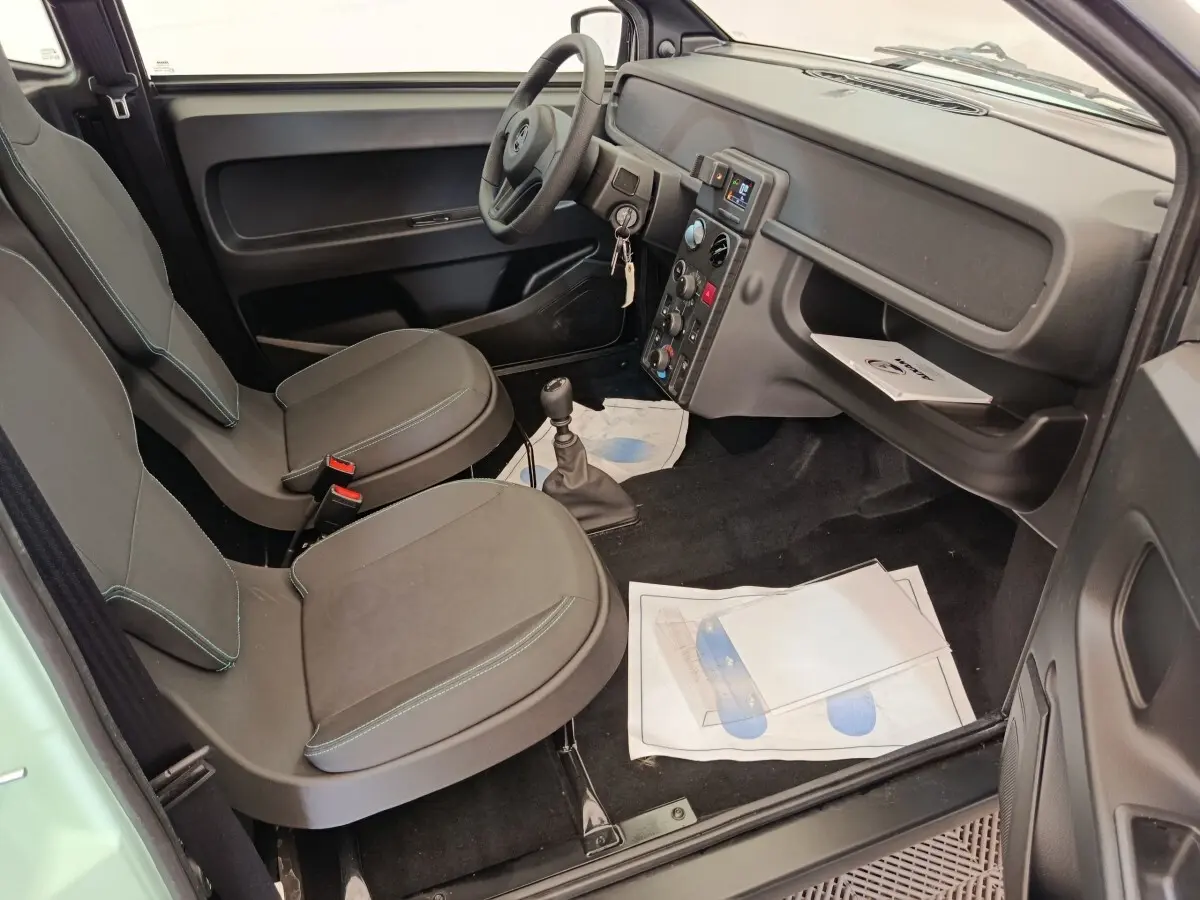 Vue intérieure côté conducteur de l'AIXAM AMBITION Easy Chic 2026, avec sièges gris et tableau de bord noir.