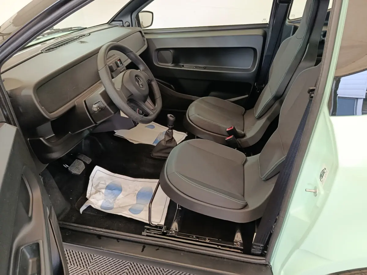 Vue intérieure côté conducteur de l'AIXAM Ambition Easy Chic 2026 vert, avec sièges gris et tableau de bord minimaliste.