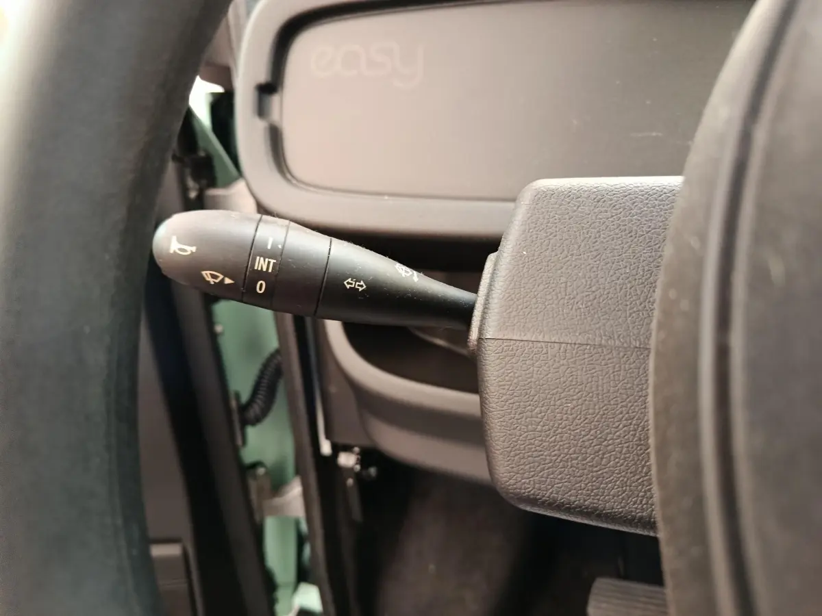 Gros plan sur la manette d’essuie-glace à gauche du volant d’une Aixam Ambition Easy Chic thermique verte.