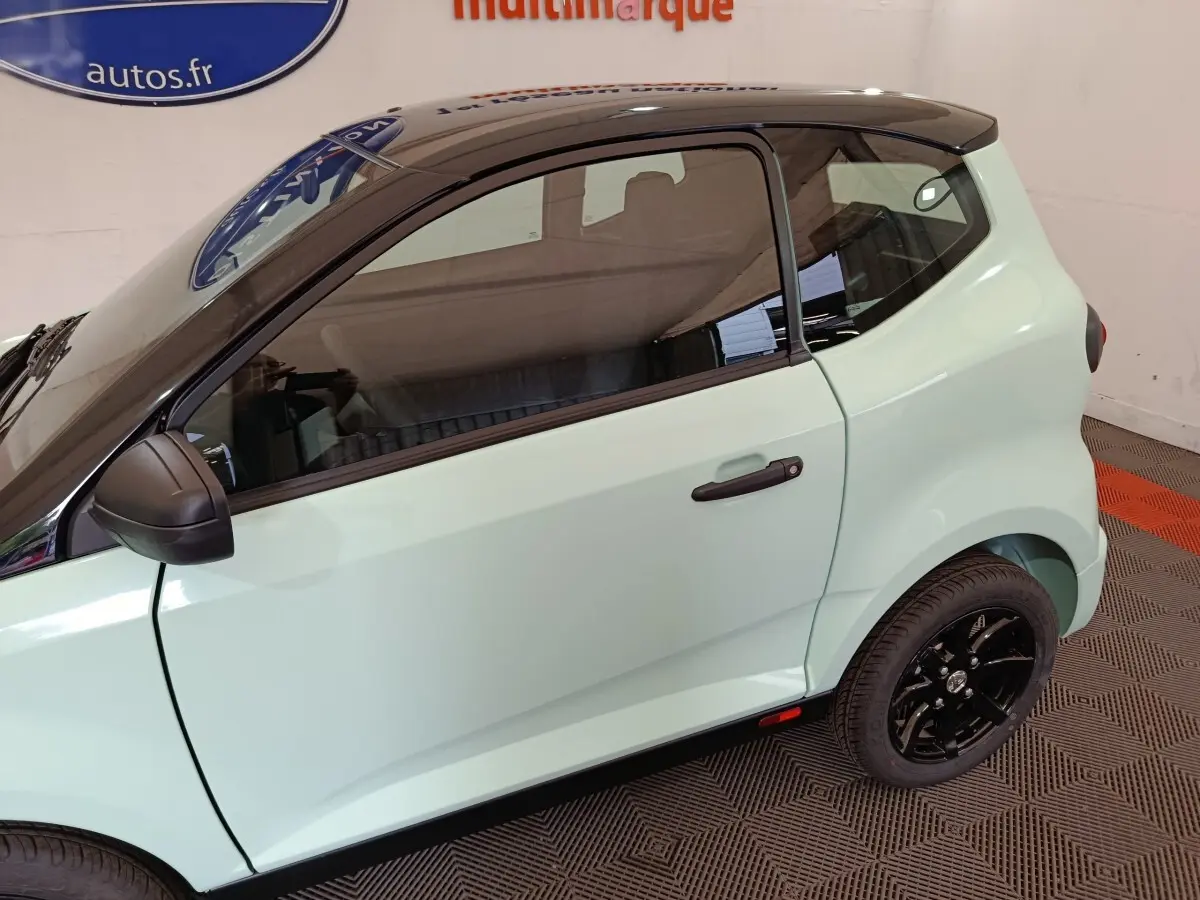 Vue latérale droite d'une Aixam Ambition Easy Chic thermique 2026 vert clair avec toit noir et jantes noires.