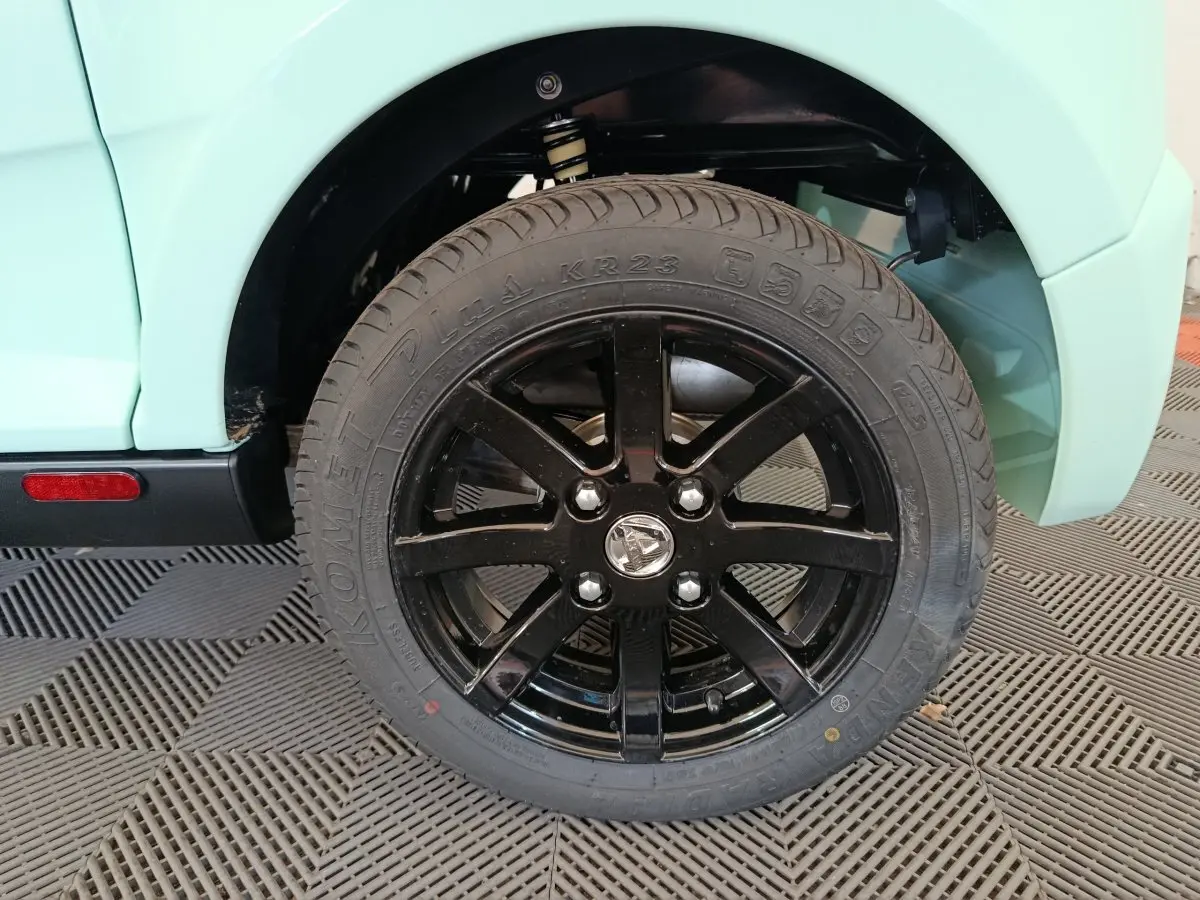 Gros plan sur la roue arrière droite noire brillante d'une Aixam Ambition Easy Chic thermique verte, année 2026.