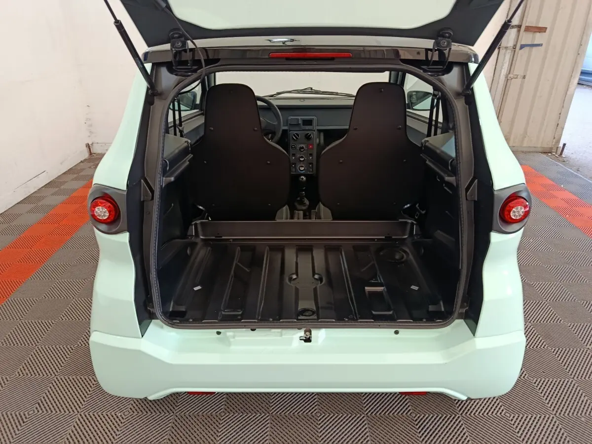 Vue arrière ouverte de l'AIXAM AMBITION Easy Chic thermique 2026 vert, montrant l'espace de coffre et les sièges noirs.