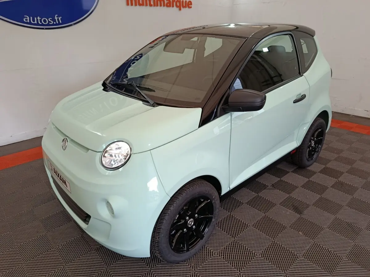 Vue 3/4 avant d'une Aixam Ambition Easy Chic thermique 2026 vert clair avec toit noir et jantes noires.