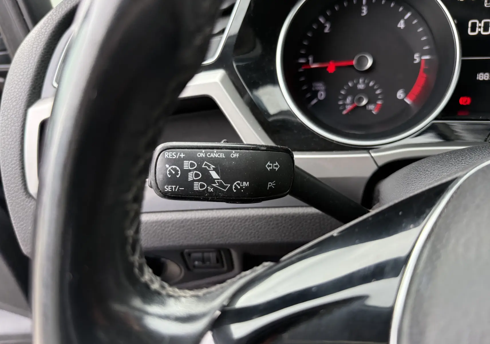 Vue rapprochée du commodo de régulateur de vitesse à gauche du volant noir dans le tableau de bord d’un Volkswagen Touran 2017.