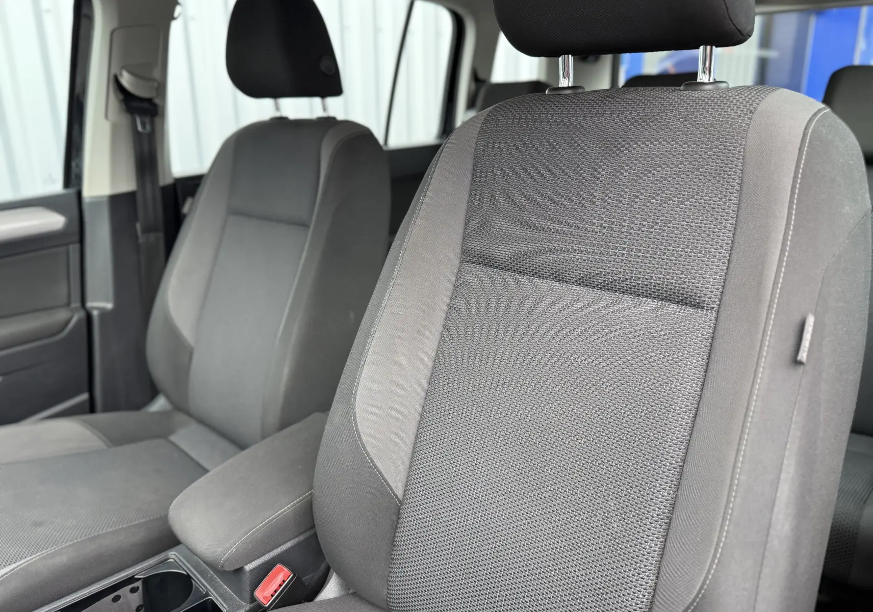 Vue intérieure rapprochée des sièges avant en tissu gris du Volkswagen Touran 2017, version 1.6 TDI Trendline 7 places.