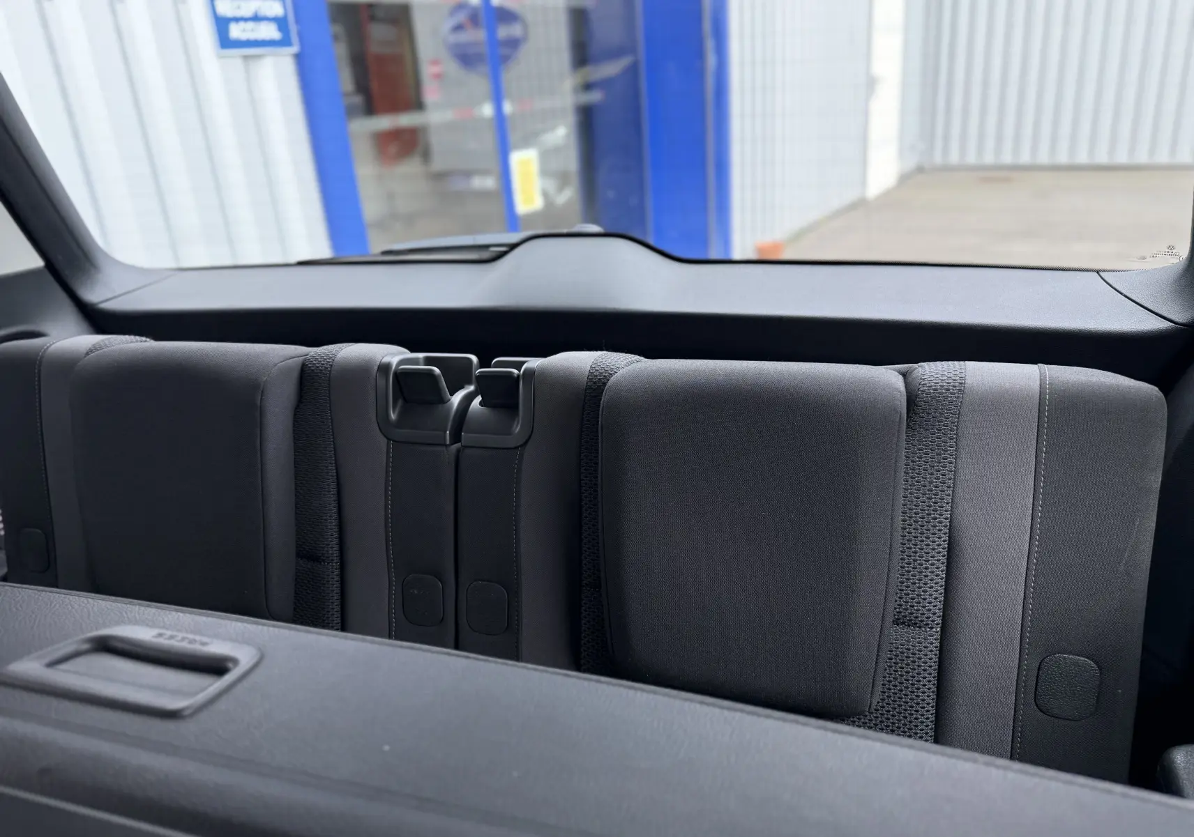 Vue intérieure arrière du Volkswagen Touran noir 2017, montrant les sièges rabattus de la troisième rangée.
