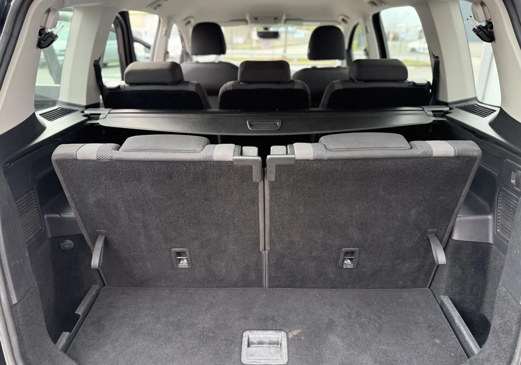Vue arrière du coffre du Volkswagen Touran noir 2017, montrant les sièges arrière relevés et l'espace de chargement.