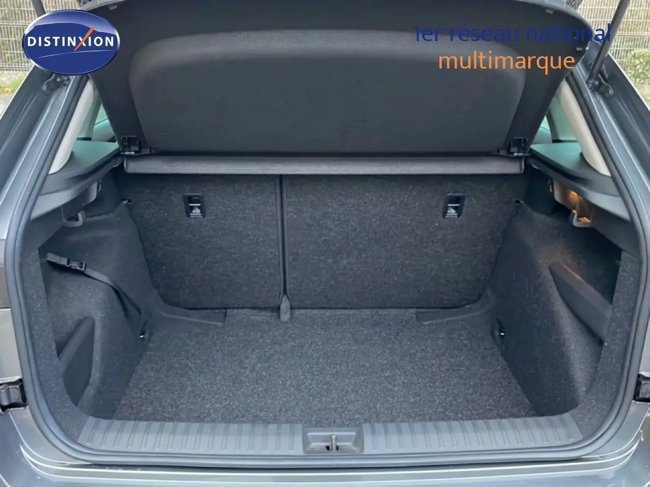 Coffre ouvert vu de l’arrière d’un Skoda Kamiq gris graphite métal, montrant un espace de chargement propre et vide.
