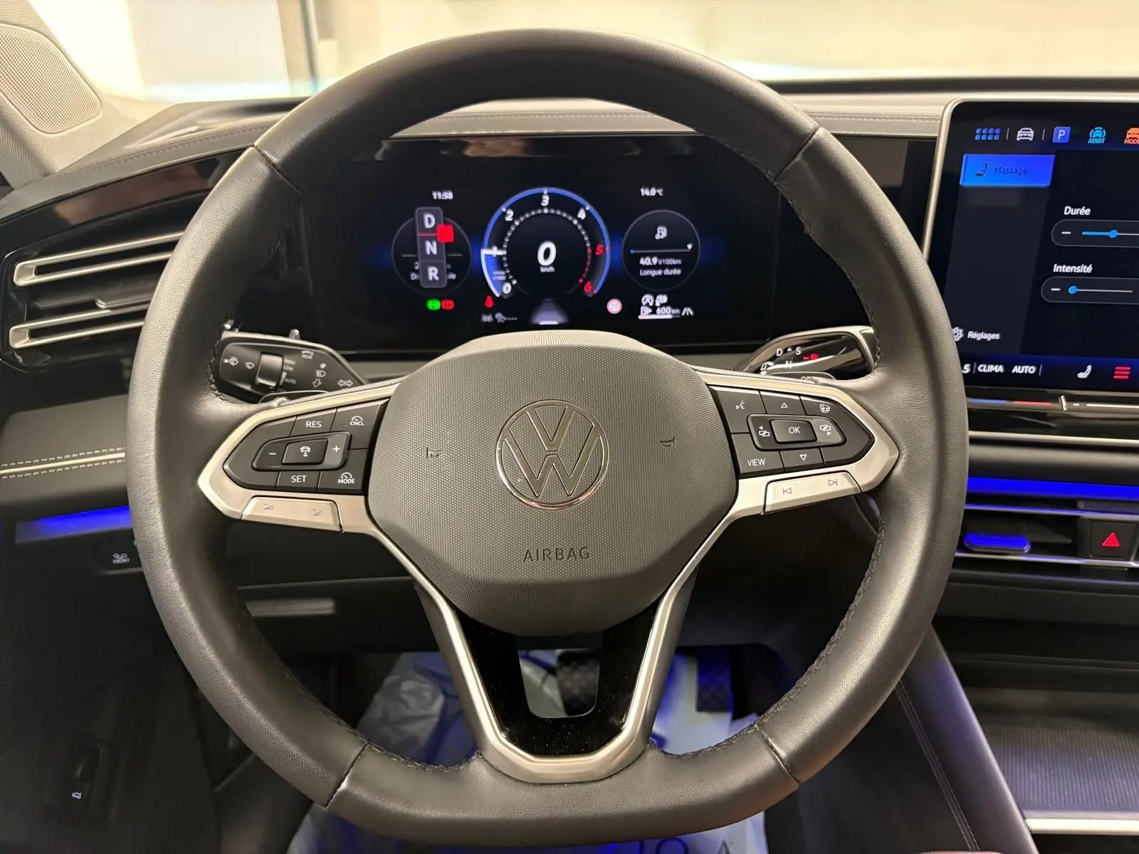 Vue centrée sur le volant noir du Volkswagen Tiguan 2.0 TDI 150 DSG7 avec tableau de bord numérique allumé.