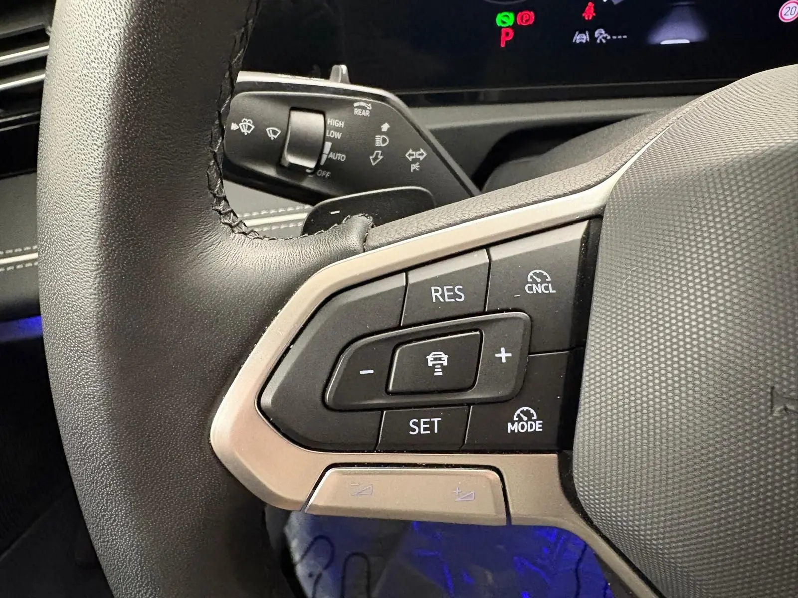 Gros plan sur les commandes au volant du Volkswagen Tiguan 2025, avec boutons de régulateur de vitesse et finition noire.