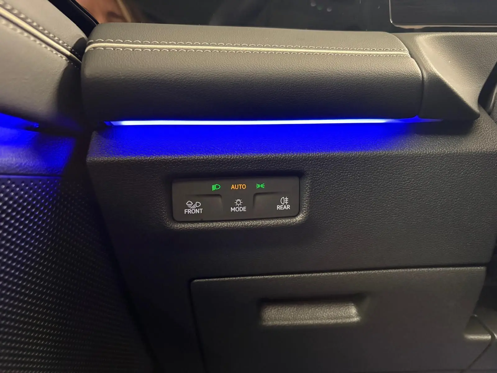 Détail intérieur côté gauche du Volkswagen Tiguan 2.0 TDI 150 DSG7 Elegance avec éclairage d'ambiance bleu et commandes des phares.