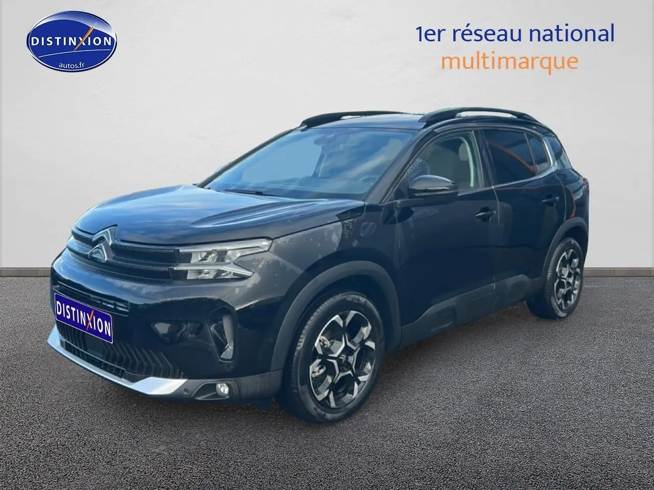 Citroën C5 Aircross noir vue 3/4 avant droit, avec jantes alu et barres de toit visibles.