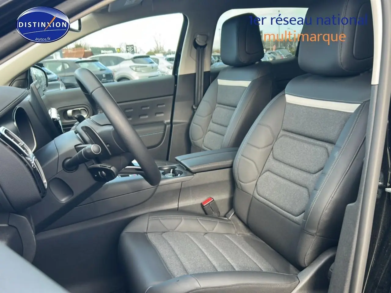 Vue intérieure côté conducteur du Citroën C5 Aircross noir, mettant en valeur les sièges en cuir et tissu gris avec accoudoir central.