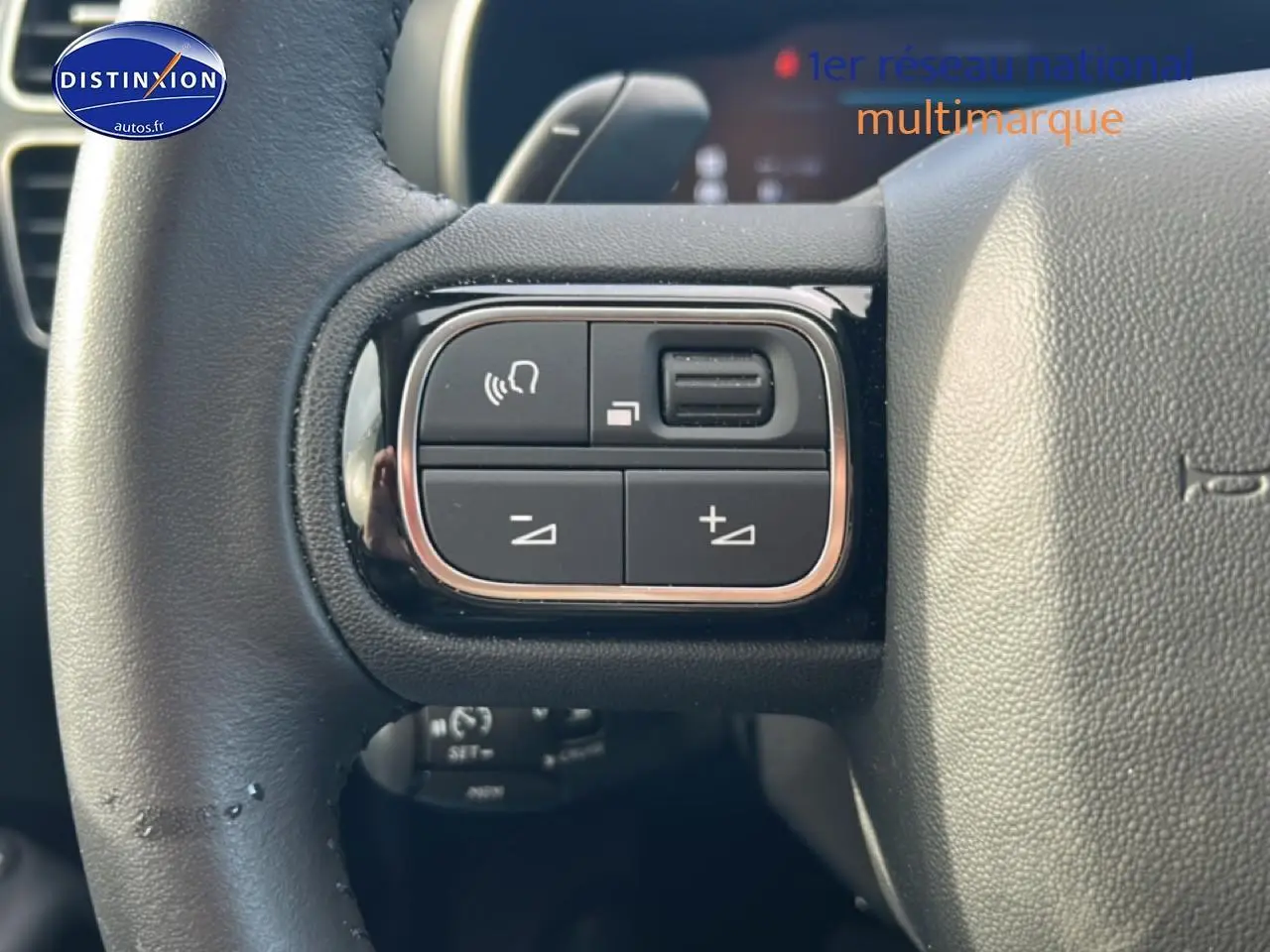 Gros plan sur les commandes multifonctions à gauche du volant cuir noir du Citroën C5 Aircross hybride 2025.