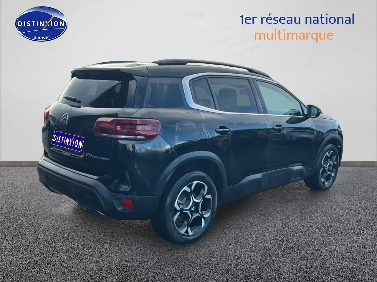 Vue 3/4 arrière droite d'un Citroën C5 Aircross noir avec jantes alu et barres de toit visibles.
