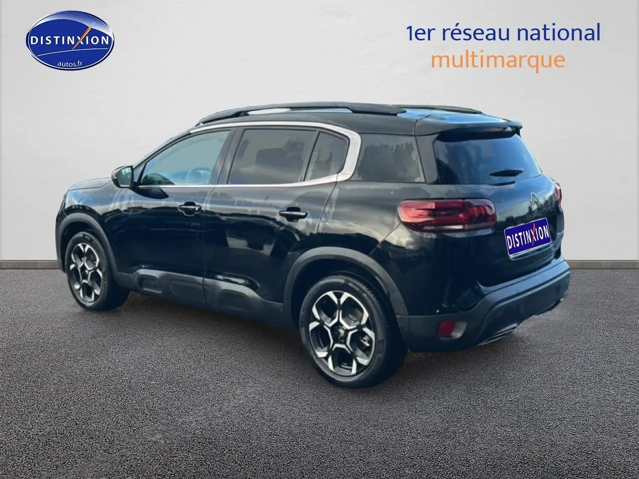 Citroën C5 Aircross noir vu en 3/4 arrière droit, avec barres de toit et jantes alu distinctives.