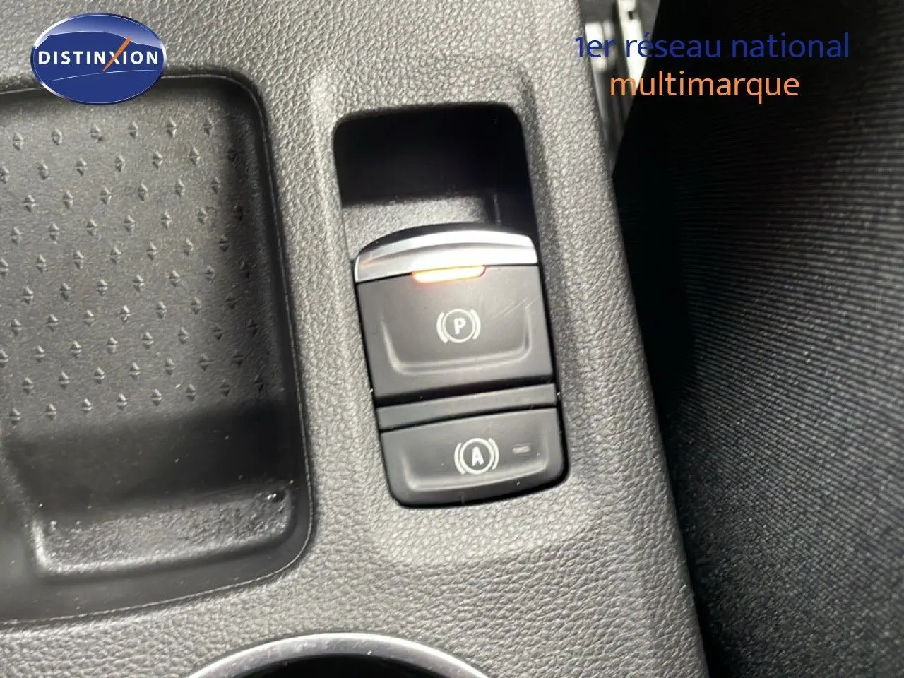 Gros plan sur les commandes de frein à main électronique et auto hold dans l'habitacle du Renault Symbioz bleu iron metal.