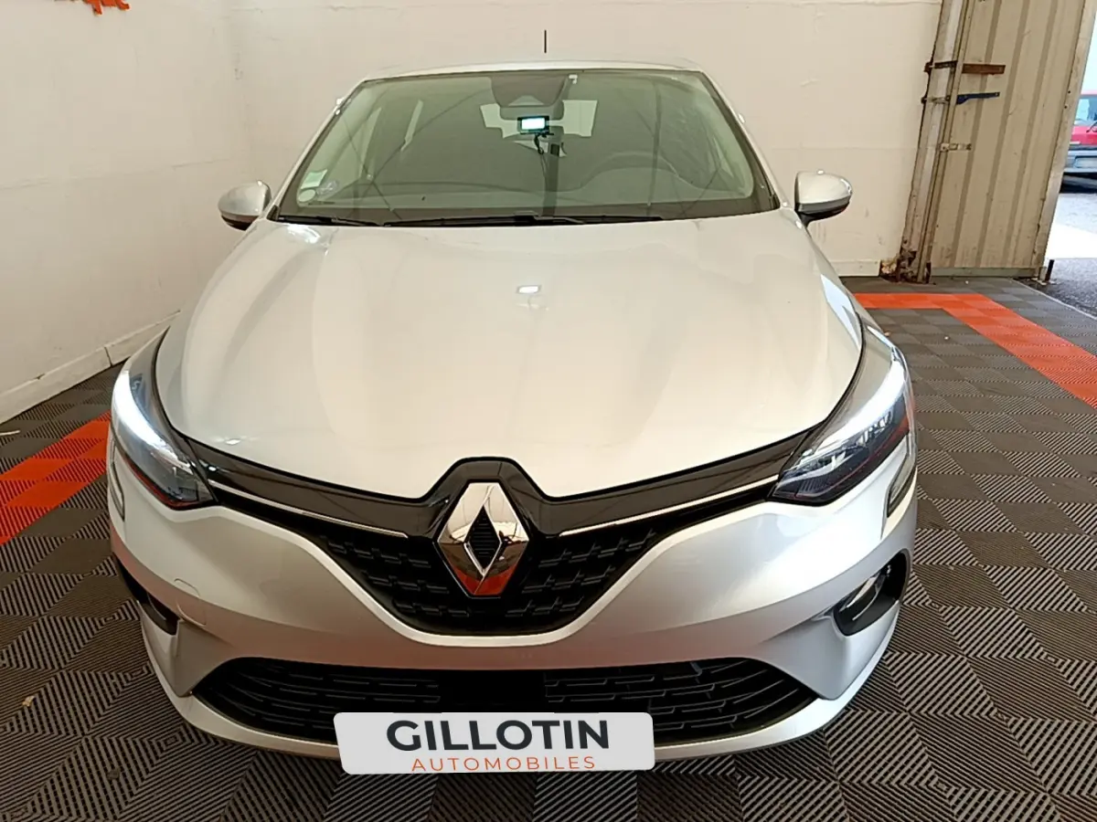 Vue avant d'une Renault Clio Business TCe 100 gris clair avec phares à LED allumés dans un garage.