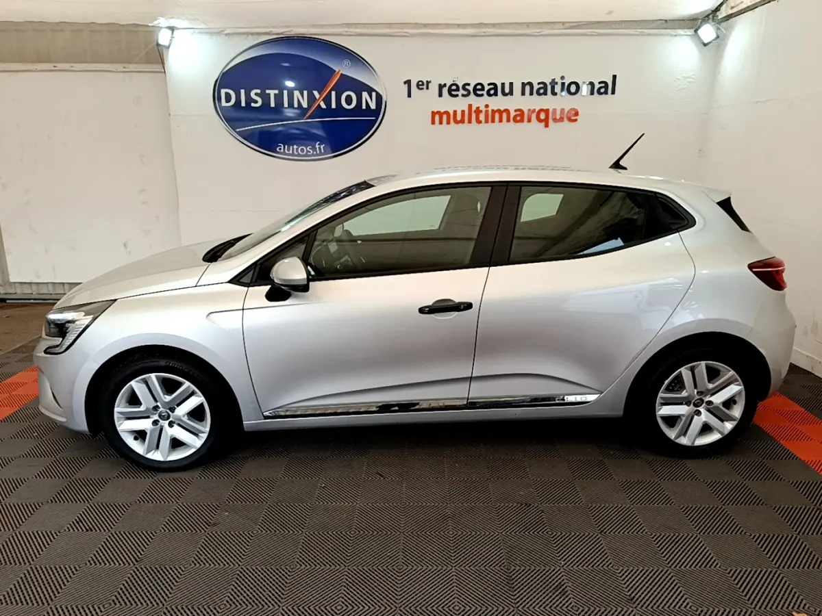 Profil côté gauche d'une Renault Clio Business TCe 100 gris clair, vue en intérieur sur fond clair avec logo Distinxion.