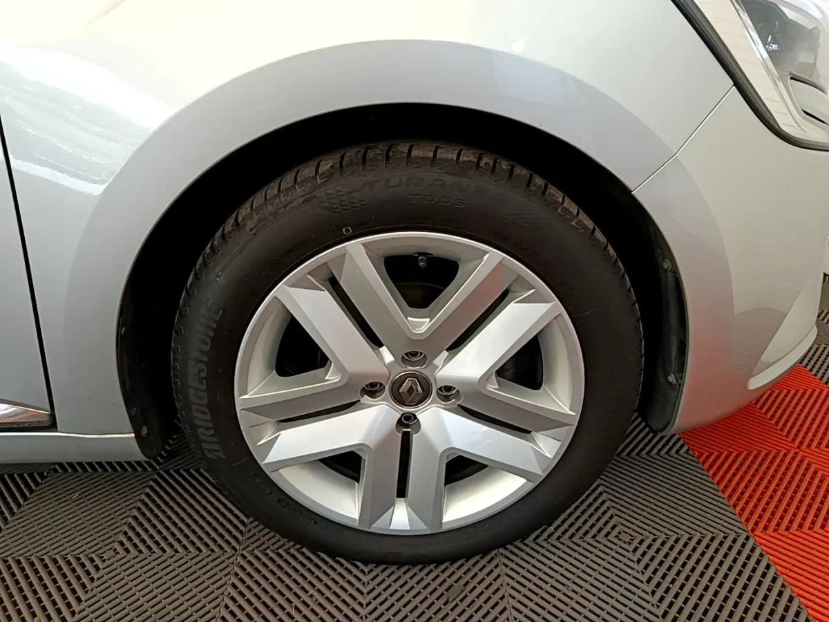 Gros plan sur la roue avant gauche gris clair d'une Renault Clio Business TCe 100 avec jante alliage distinctive.