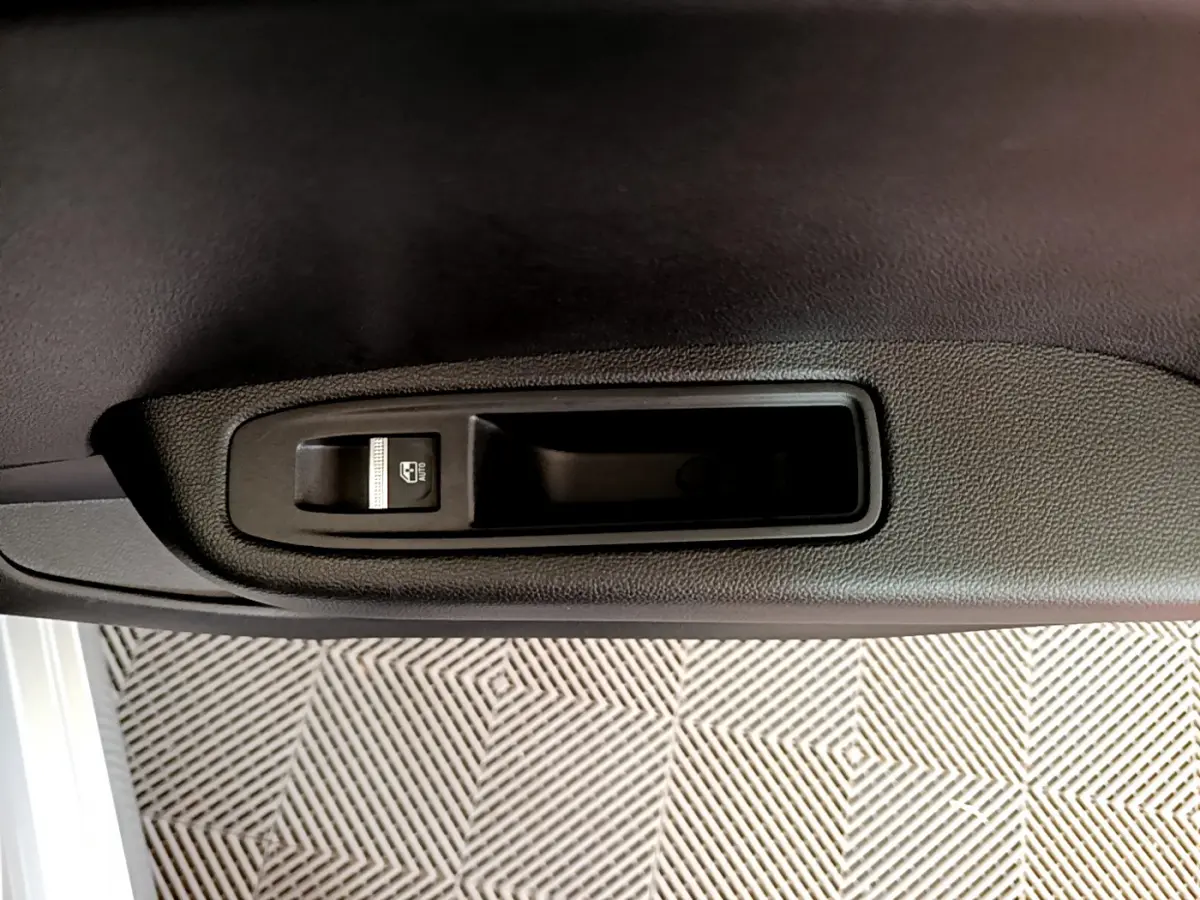 Détail de la commande de lève-vitre électrique sur la porte intérieure d’une Renault Clio Business gris clair.