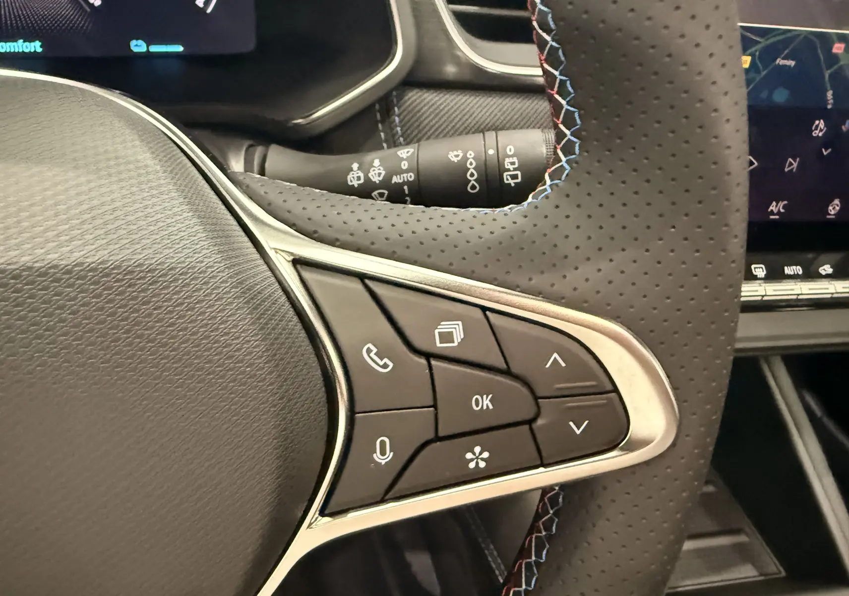 Gros plan sur les commandes multifonctions à droite du volant perforé noir du Renault Captur E-Tech blanc nacré 2026.