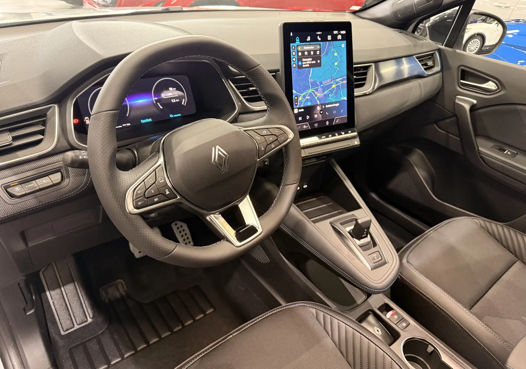 Vue intérieure côté conducteur du Renault Captur E-Tech 2026, volant multifonction, écran tactile vertical et sellerie noire.