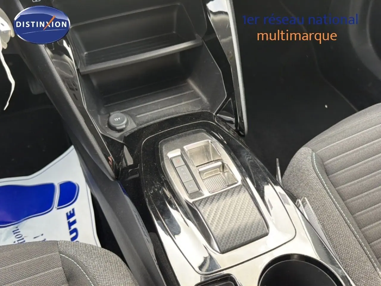 Vue rapprochée de la console centrale noire brillante avec levier de vitesses automatique et siège tissu gris côté droit.