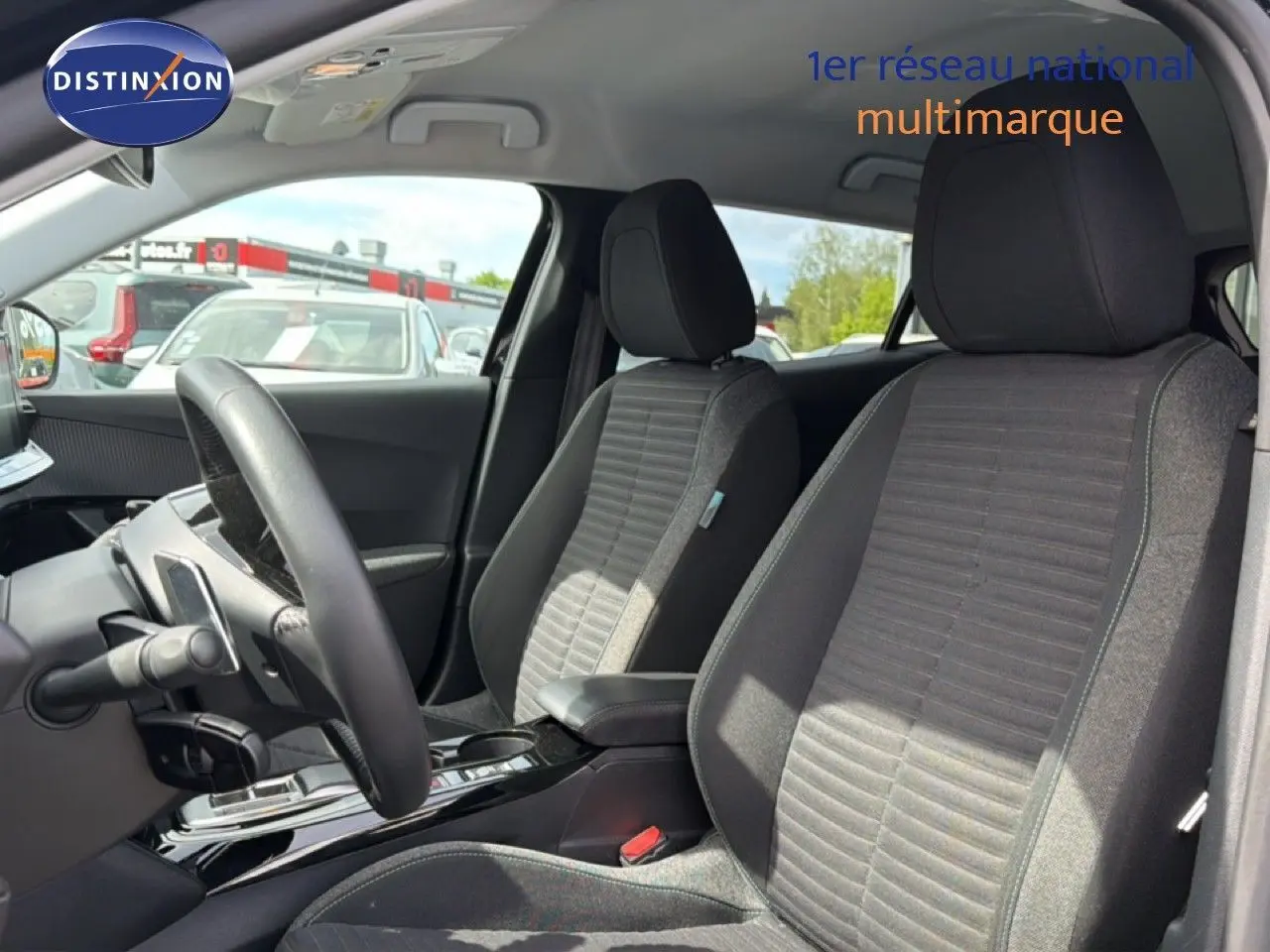 Vue intérieure côté conducteur du Peugeot 2008 2022, sièges tissu noir et console centrale brillante.