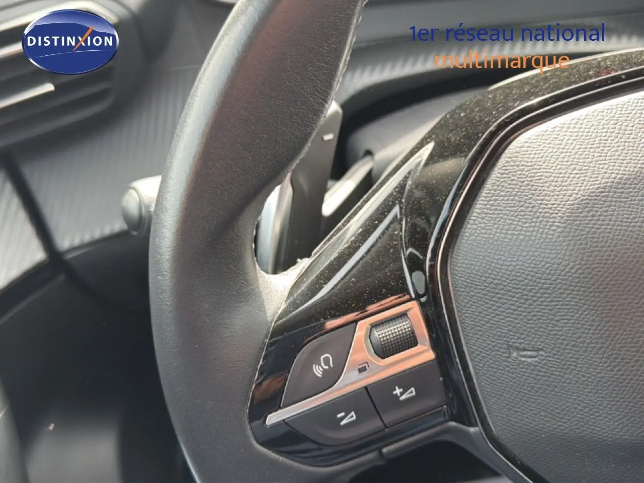 Gros plan sur le côté gauche du volant noir du Peugeot 2008 2022, avec commandes audio intégrées.