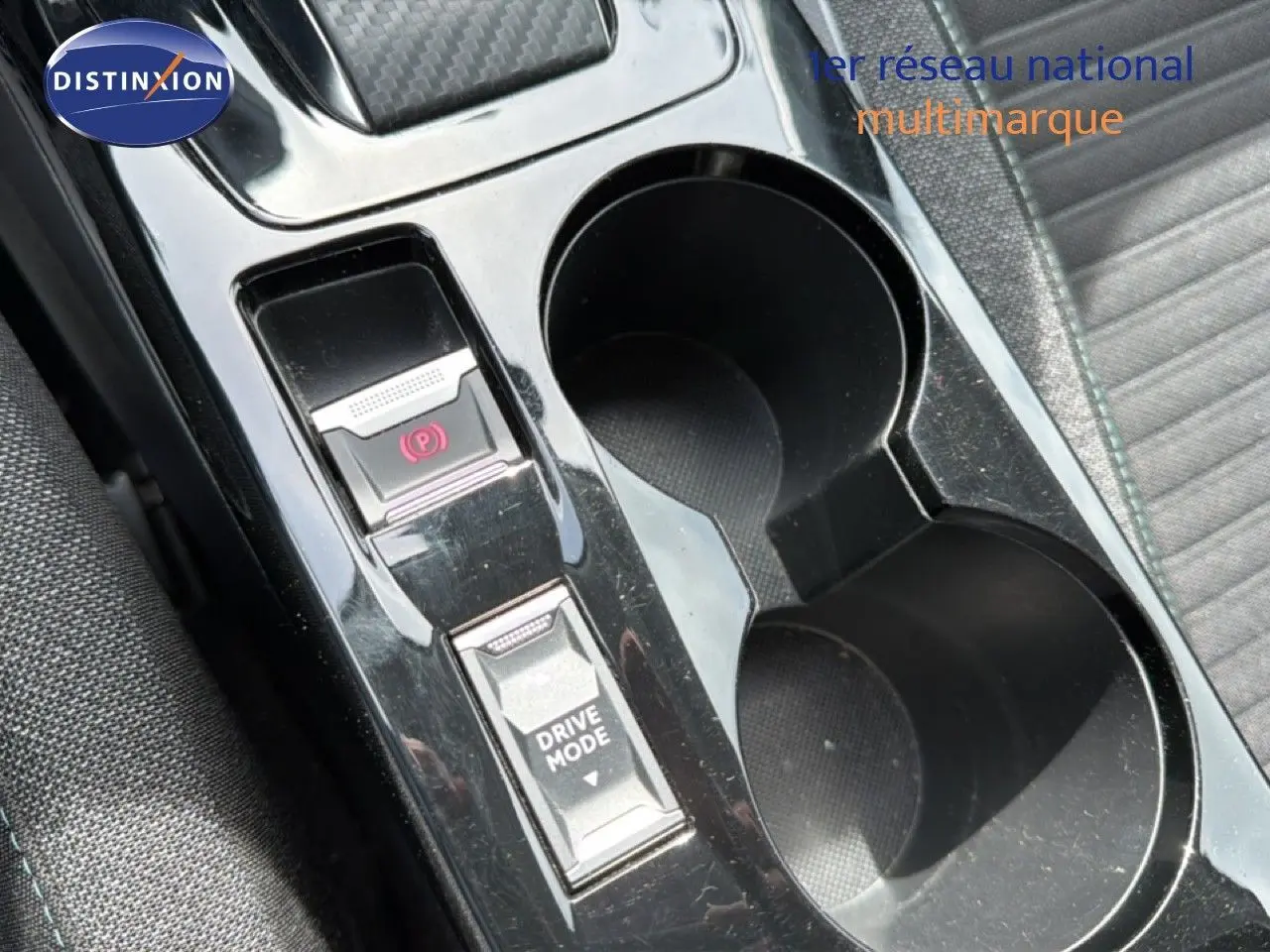 Gros plan sur la console centrale noire perle métal du Peugeot 2008, avec bouton frein à main électronique et sélection drive mode.