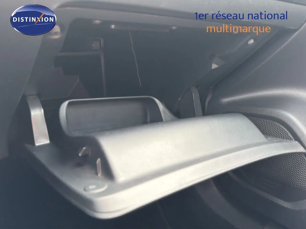 Gros plan sur la boîte à gants ouverte de la Peugeot 2008 noire perle métal, intérieur sombre et moderne.