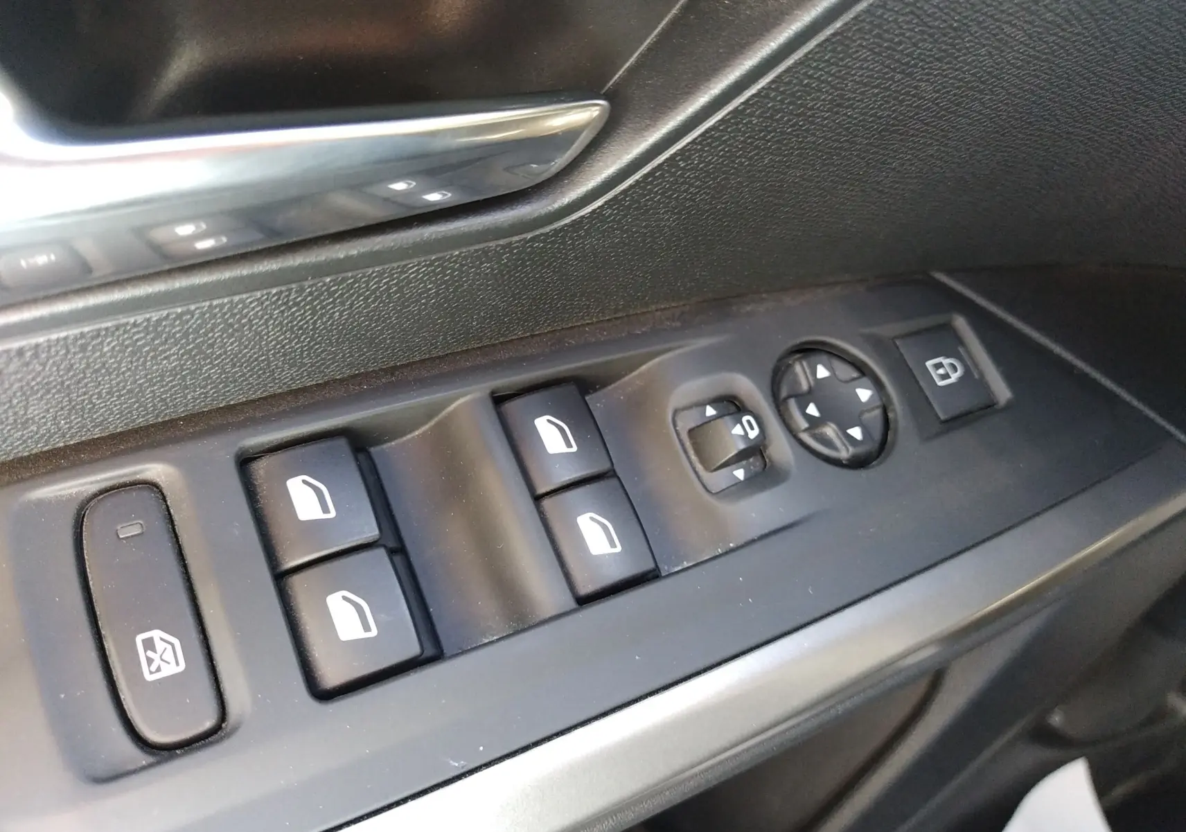 Gros plan sur les commandes de lève-vitres et réglages des rétroviseurs côté conducteur, intérieur noir du Peugeot 3008 Hybrid.