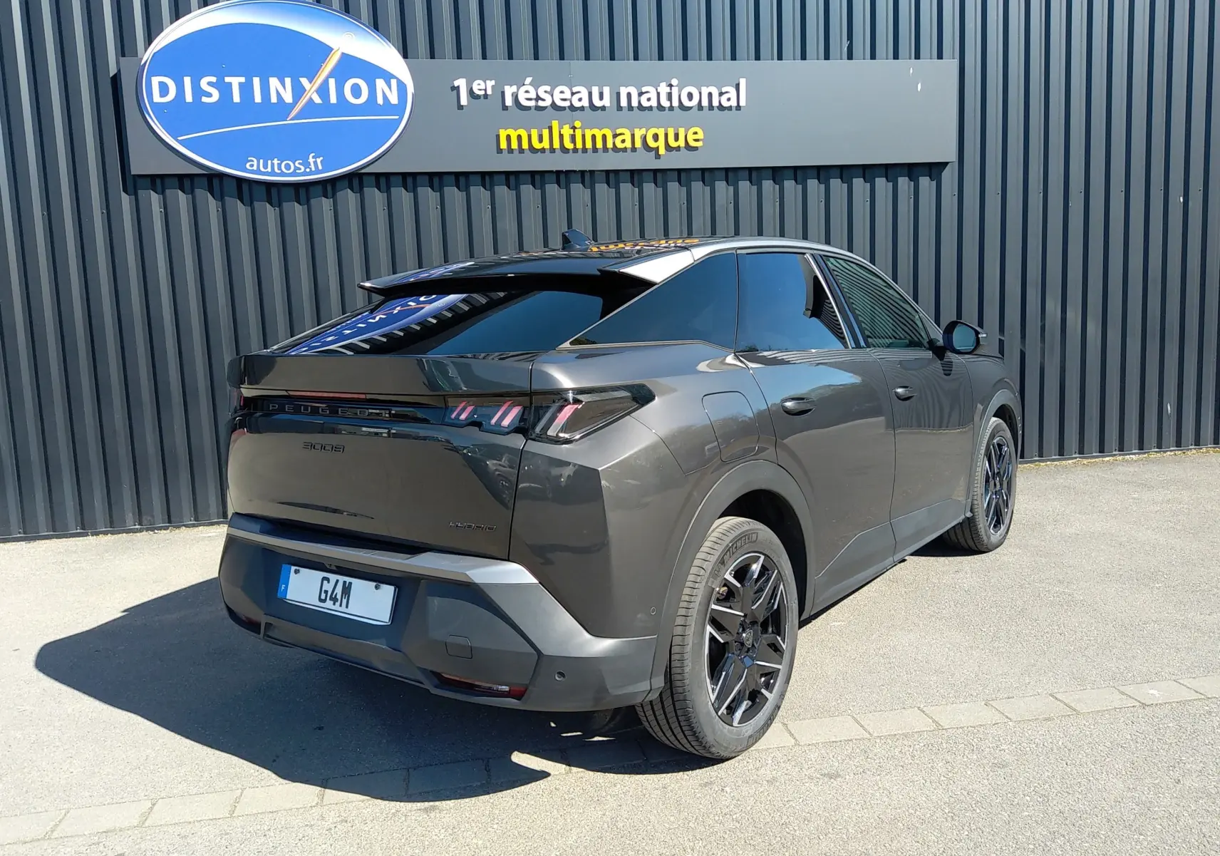 Vue 3/4 arrière droite du Peugeot 3008 Nouveau Hybrid 136 Allure gris titane avec jantes noires et vitres teintées.